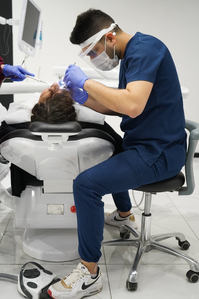 Dentist wearing protective masks and gloves performing treatment on patient in a modern clinic.