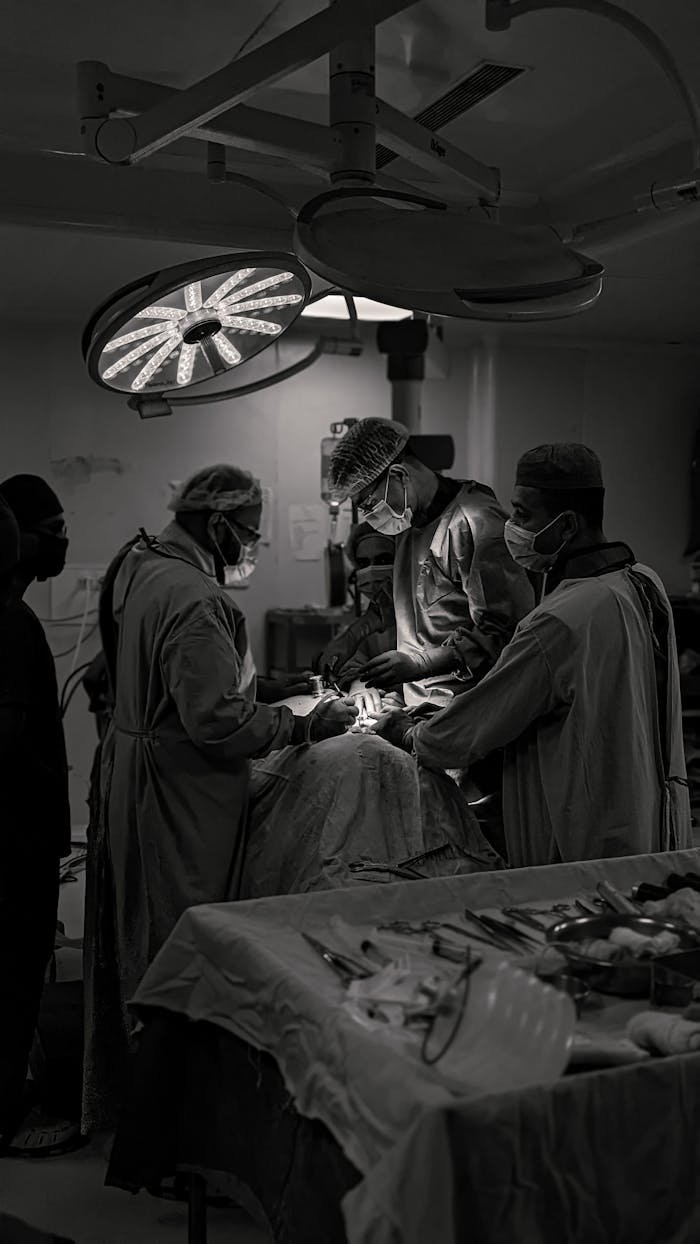 Team of surgeons in an operating room conducting surgery in black and white.