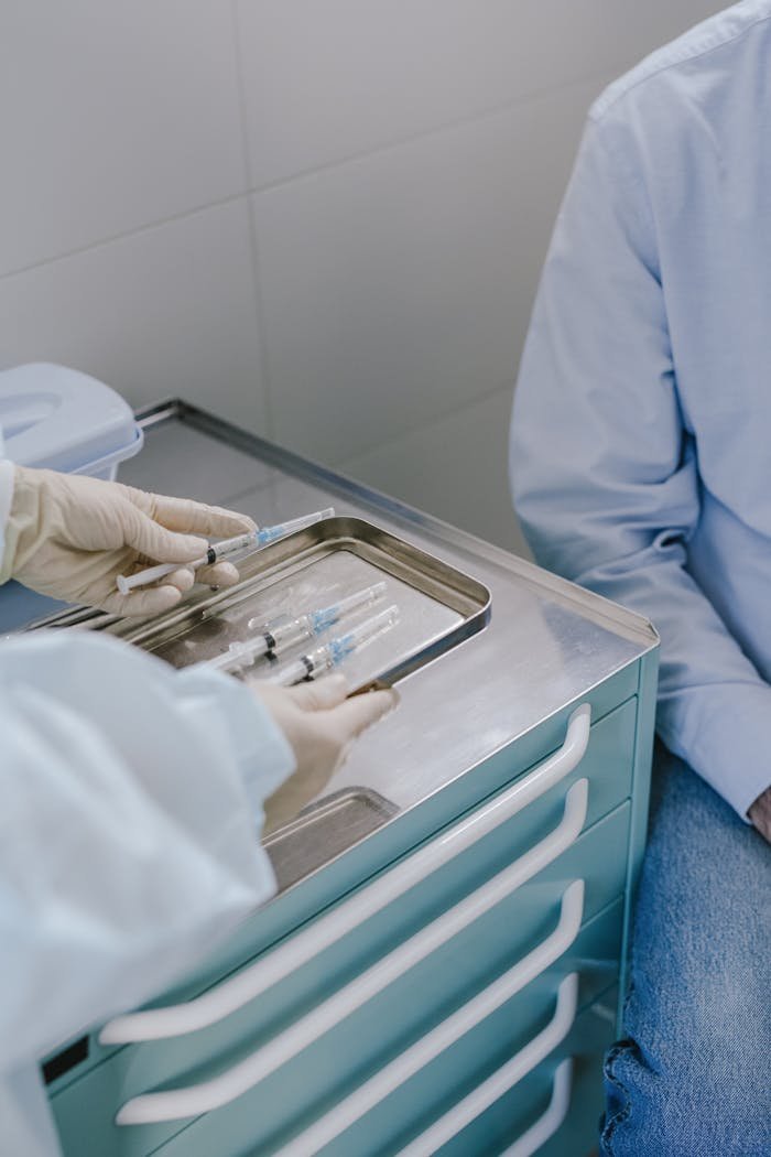 Doctor prepares syringes on a tray for a patient in a clinical setting.